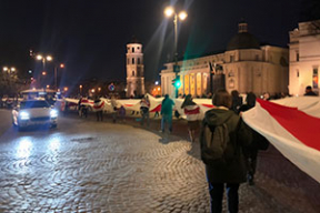 Сотни бело-красно-белых флагов в центре Вильнюса, и один, который несут тысячи, в 300 метров